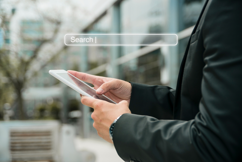 Man in suit holds tablet, searching on digital interface outdoors